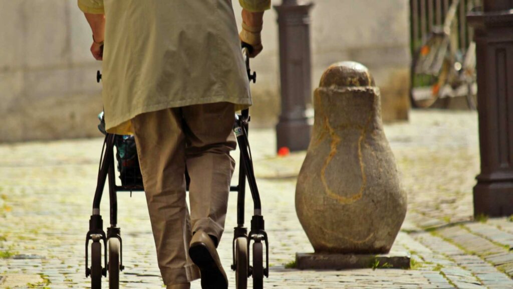 Person walking on cobble stone with a rollator